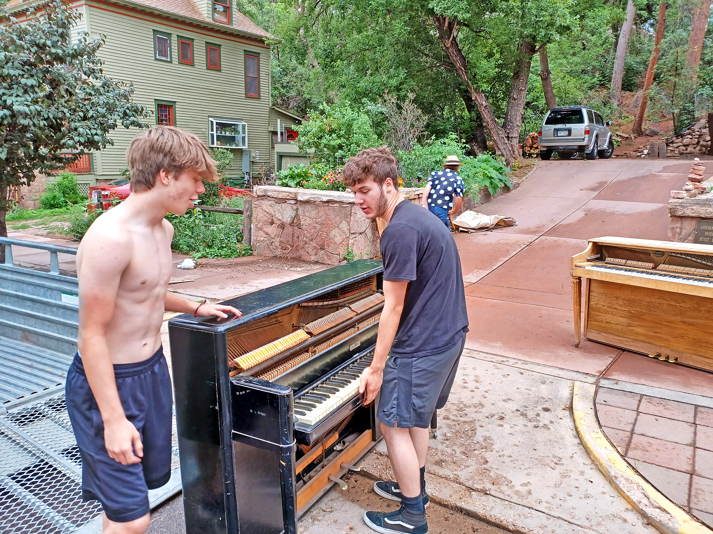 Courtesy of Rolf Jacobson Local resident Lukas Jacobson, right, helps Manitou Springs High School student Camden Jacobson move a new piano onto Manitou Avenue on Saturday, July 30. They removed the old piano that has been decomposing for several years.