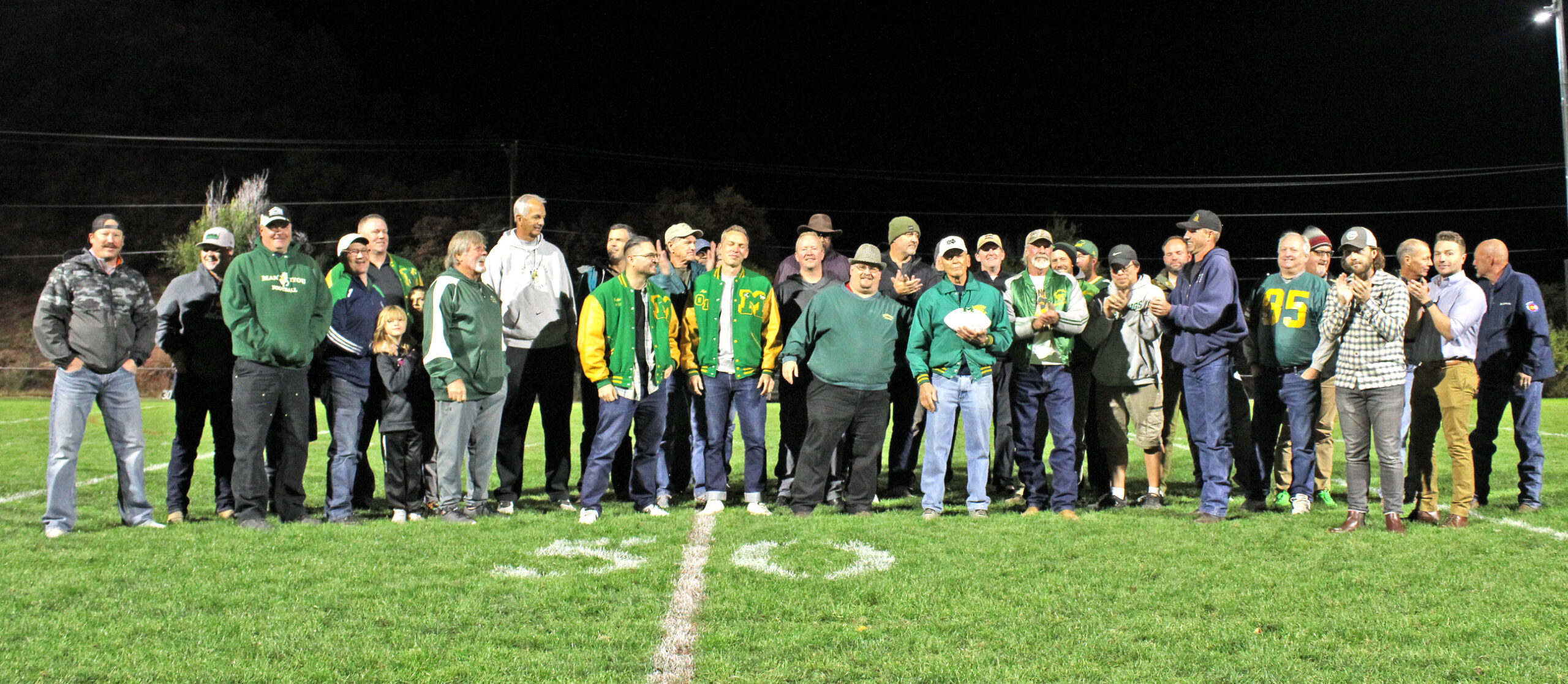 Photo by Daniel Mohrmann. Former players and coaches gather at halftime of the Oct. 21 game against La Junta to honor longtime Manitou football coach George Rykovich.